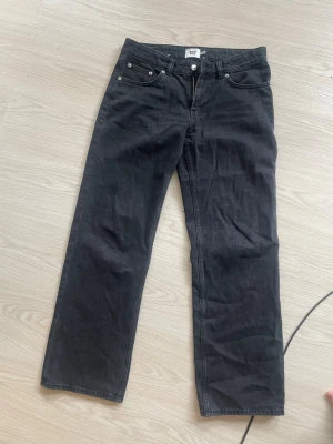 Svarta low rider jeans från 157 - Svarta jeans från 157 med low rider-passform. Klassisk femficksmodell med raka ben och knappgylf. Snygga att styla med sneakers eller boots. Materialet är denim i bomull.