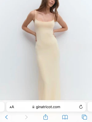 Ljusgul  långklänning från Gina Tricot - Elegant ljus långklänning från Gina Tricot med smala axelband och figurnära passform. Klänningen har en enkel, stilren design och är tillverkad i ett mjukt material som ger en bekväm känsla. Perfekt för sommarens alla tillfällen.