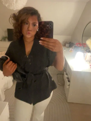 Svart kofta med knyte Zara - Snygg svart kofta med knytskärp i midjan och djup V-ringning. Koftan har en avslappnad passform och är perfekt för att lyfta vilken outfit som helst. Materialet ser ut att vara mjukt och följsamt, vilket ger en modern och trendig look.