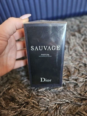 Dior Sauvage Parfum 100ml - Dior Sauvage Parfum är en ikonisk herrdoft i en elegant mörkblå och svart förpackning. Flaskan rymmer 100 ml och har en stilren design med tydlig Dior-logga. Perfekt för dig som gillar exklusiva och fräscha parfymer.