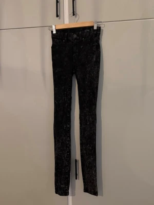 Svarta skinny jeans - Säljer ett par svarta skinny jeans med  hög midja. Jeansen har klassisk femficksdesign, bälteshällor och knappgylf. Ska va lite ”tvättade” (så jag bäst kan beskriva mönstret) ca 90cm långa. Från DRDENIM.