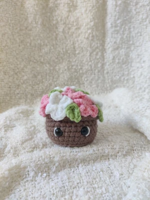 Virkad blomkruka  - Virkad blomkruka med rosa och vita blommor. Cirka 7 cm bred och 7 cm hög. Har tre likadana, därav tre annonser. 