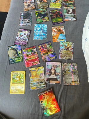 Samling Pokémonkort GX/EX/V Full Art - Säljer en samling Pokémonkort med flera GX, EX och V Full Art-kort. Blandade färger och motiv med holografiska effekter, inklusive populära karaktärer som Pikachu, Raichu och Charizard. Korten är tillverkade i laminerad kartong och har både klassiska och moderna designer. Perfekt för samlare eller Pokémonfans.