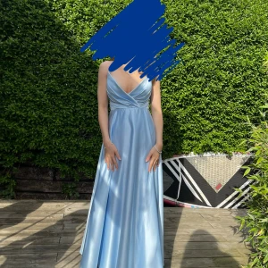 Ljusblå balklänning från JJ’s House  - Säljer min vackra ljusblå balklänning från 9ans bal, med smala korsade axelband och v-ringning. Klänningsmodellen heter Donjeta och är i  satinliknande tyg med markerad midja som ger en fin siluett. Använd en gång, därefter tvättad. Upplagd av sömmerska att passa mig som är 168 cm och hade ballerinaskor under kvällen. Nypris inkl frakt från usa 1800 kr.