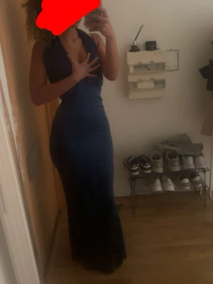 Marinblå långklänning med halterneck - Snygg marinblå långklänning med halterneck och djup urringning framtill. Klänningen har en elegant, figurnära passform och är tillverkad i ett glansigt material som ger en lyxig känsla. Perfekt för speciella tillfällen när du vill sticka ut. OBS! Kan gå ner lite pris vid seriöst intresse:)