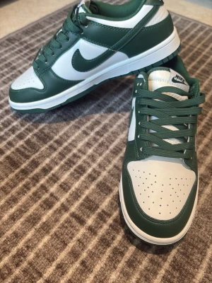Nike Dunk Low gröna och vita sneakers - Säljer dessa aldrig använts, dem är verkligen i toppskick. Du får med shoe trees också på köpet 