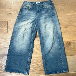 Wide jeans från BDG med rå kant - Blå jeans från BDG med breda ben och rå, fransig kant nertill. Jeansen har en ljus tvätt med slitningar framtill och bakfickor, varav ena bakfickan har BDG-logga. Klassisk femficksmodell och hög midja. Perfekta för en avslappnad streetstil.