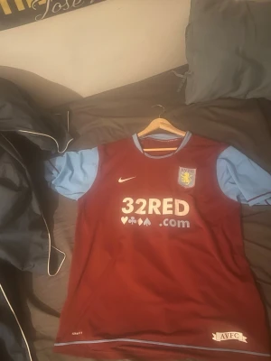 Aston Villa och Wolves matchtröjor - Två snygga fotbollströjor: en vinröd Aston Villa-tröja från Nike med ljusblå ärmar och klubbmärke, samt en orange Wolverhampton-tröja från Adidas med svarta detaljer och klubbmärke. Perfekta för fotbollsträning eller att bära på matchdag! Äkta fotbollströjor finns bevis, går och köpa separat också