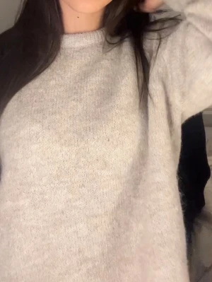 Beige stickad tröja i mjuk ullmix - Enkel och stilren beige stickad tröja med rund halsringning och långa ärmar. Tröjan har en avslappnad passform och är gjord i en mjuk ullmix som känns skön mot huden. Perfekt för lager på lager under kyliga dagar.