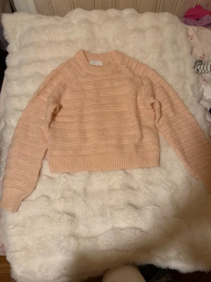 Ljusrosa stickad tröja Samsa på Ullared - Supersöt ljusrosa stickad tröja från Samsa Collection på Ullared. Tröjan har rund hals, långa ärmar och ribbade muddar vid ärmslut och nederkant. Mjuk och fluffig känsla, perfekt för kyliga dagar. Enkel men snygg design som passar till det mesta. Peach/coral färg. 