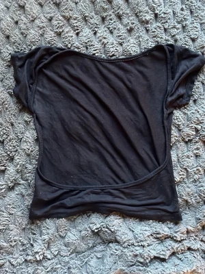 Svart croppad topp med kort ärm - En enkel svart croppad topp i mjukt bomullsmaterial. Toppen har korta ärmar och en figurnära passform med rund halsringning. Perfekt att styla med höga jeans eller kjol för en trendig look.