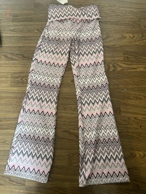 Mönstrade yogapants Kappahl - Säljer ett par snygga yoga leggings från Kappahl i storlek 164. De har ett färgglatt zigzag-mönster i rosa, vitt och brunt. Modellen har utsvängda ben och bred resår i midjan. 