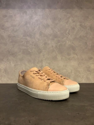 Axel Arigato Clean 90 - Snygga beige sneakers från Axel Arigato i mocka med matchande snörning och vit gummisula. Klassisk låg modell med stilren design och diskret logga på sidan. Perfekta för dig som gillar minimalistisk stil och vill ha något som funkar till det mesta. I mycket bra skick, endast använda ett fåtal gånger!