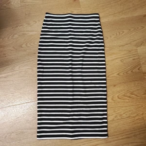 Midi svartvit randig långkjol - Säljer en svartvit långkjol med horisontella ränder. Kjolen har en rak och tight passform som ger en clean och stilren look. 