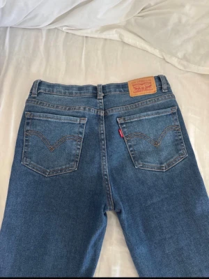 Blå bootcut jeans från Levi's - Säljer ett par klassiska blå Levi's jeans med bootcut-modell och medellåg midja. har använt max 5 gånger. väldigt sköna och snygga. storlek 156cm men är 160cm och passar mig perfekt!