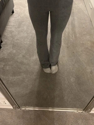 Grå ribbade mjukisbyxor - Säljer ett par grå mjukisbyxor med bred ribbad midja och raka ben. Byxorna är i mjukt och stretchigt material som sitter skönt på kroppen. Perfekta för chill dagar hemma eller när du vill vara bekväm men ändå se snygg ut.