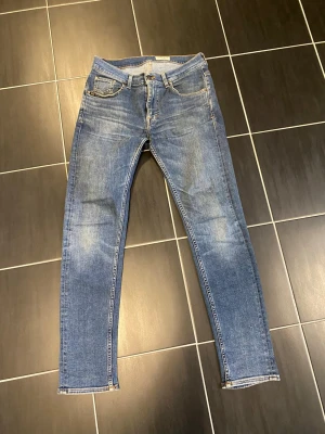 Tiger of sweden jeans - Snygga blå slim fit jeans med klassisk femficksdesign och lätt slitna detaljer. Jeansen har normalhög midja och smala ben. Tillverkade i ett stretchigt denimtyg för extra komfort. Perfekta till en avslappnad streetstyle-look. Storlek 30/32