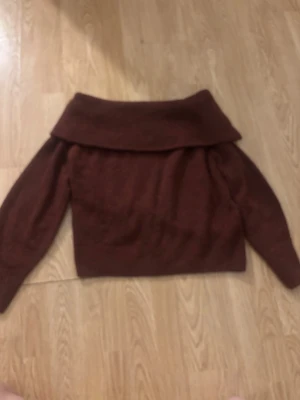 Vin röd off shoulder stickad tröja - Mysig brun stickad tröja med off shoulder-krage och långa ärmar. Perfekt för dig som gillar en avslappnad men ändå trendig look. Materialet ser mjukt och skönt ut