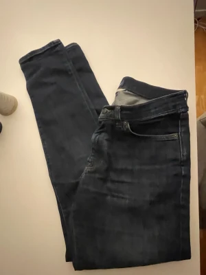 Mörkblå skinny jeans - Snygga mörkblå skinny jeans med klassisk femficksdesign och normal midja. Jeansen har smal passform och är tillverkade i ett stretchigt denimtyg som sitter bekvämt. Perfekta till en avslappnad look och lätta att matcha med olika stilar.