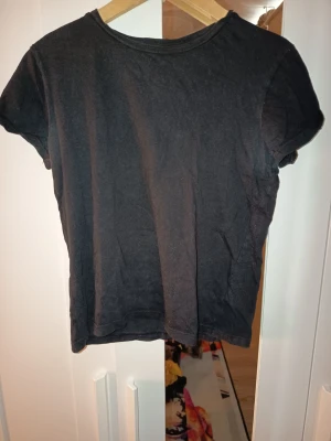 Svart basic t-shirt - En enkel svart t-shirt med rund hals och korta ärmar. Perfekt till jeans eller shorts och funkar året runt. T-shirten har en klassisk passform och är tillverkad i mjukt material.