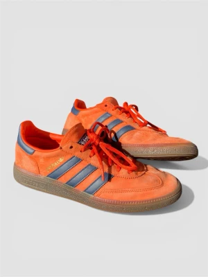 Adidas Spezial orange/blå sneakers - Snygga Adidas Spezial sneakers i orange mocka med klassiska blå ränder på sidorna och matchande blå detaljer vid hälen. Skorna har röda snören och en brun gummisula. 