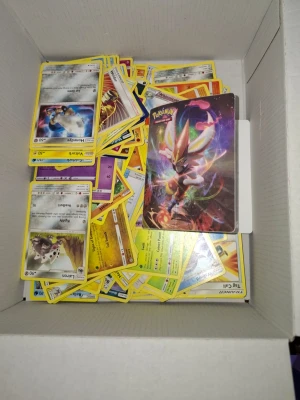 Stor samling Pokémonkort - Säljer en stor samling Pokémonkort med blandade motiv och färger. Innehåller både vanliga och holografiska kort, bland annat Zygarde GX och Cinderace. Korten är av papper och plast, och flera olika generationer och typer ingår. Perfekt för samlare eller Pokémonfans.