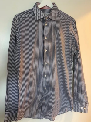 Randig blå/vit ETON - Klassisk långärmad skjorta med smala blå och vita ränder. Skjortan har knappar framtill och på manschetterna samt en stilren krage. Perfekt för dig som gillar en clean och tidlös look.