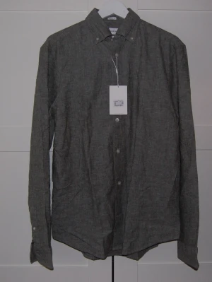 Grå linneskjorta från These Glory Days (Volt)  - Stilren grå skjorta i linne från Volt. Skjortan är helt ny och bara testad ej använd, därför lappen sitter kvar. Sitter väldigt skönt och blir väldigt snyggt med vit tröja under. 