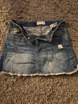 Jeanskjol - Säljer en kort blå jeanskjol med fick på baksidan. Kjolen har en liten fläck på vänster sida nedtill, som syns på bilden. Annars inga övriga defekter. Från Zara. 