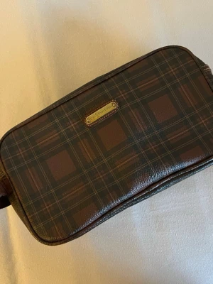 Polo väska  - En snygg Polo clutch väska i brunt och mörkgrönt rutigt mönster. Perfekt för att samla småsaker eller använda som sminkväska.