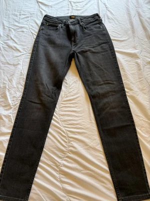 Svarta skinny jeans från Lee - Snygga svarta skinny jeans från Lee, modell Scarlett High med hög midja. Jeansen har klassisk femficksdesign, dragkedjegylf och Lee-logga på knappen. Perfekta för en trendig och avslappnad stil.