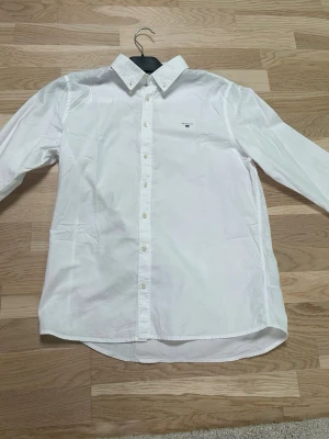Vit skjorta med knappstängning - Klassisk vit Gant skjorta med lång ärm och knappar framtill. Riktigt snygg nu till våren och sommar! Säljes pga att jag växt ur den. Frågor? Fråga!!!