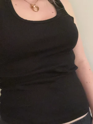 Svart ribbad linnetopp - Säljer en svart ribbad linnetopp med rund halsringning. Toppen är ärmlös och har en tight passform som sitter snyggt på kroppen. Perfekt att styla med jeans eller kjol för en enkel och clean look. Pris kan alltid diskuteras