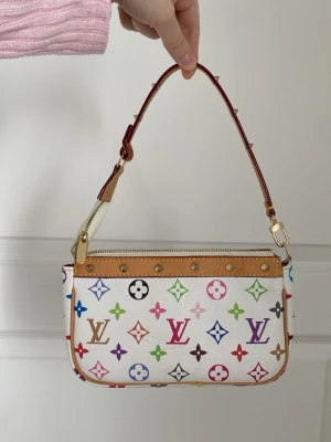 Pochette väska lv - Endast inspirerad. Perfekt accessoar för dig som vill sticka ut med färg och lyxig design. Har några märken