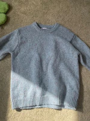 Ljusgrå stickad tröja från Zara - Mysig ljusgrå stickad tröja från Zara med färgglada små prickar i garnet. Tröjan har rund halsringning, ribbade muddar och avslut. Perfekt för lager på lager och enkel att matcha med jeans eller kjol.