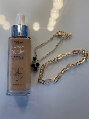 L'Oréal True Match Nude Plumping Tinted  Serum 4-5 Medium - L'Oréal Paris True Match Nude Plumping Tinted Serum i nyansen 4-5 Medium. Flytande foundation med pipett, innehåller 1% hyaluronsyra för återfuktning. Ger en naturlig finish och lätt täckning. Flaskan är i glas med silverfärgat lock. 2 armband som kommer med på köpet. 