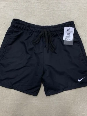 Svarta shorts från Nike med snörning - Svarta shorts från Nike med klassisk logga på benet och snörning i midjan. Perfekta för träning eller chill, med elastisk midja och lätt material som ger skön passform.