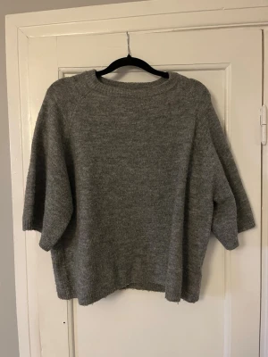 Grå oversized stickad tröja - Mysig grå stickad tröja med avslappnad, oversized passform och trekvartsärmar. Tröjan har rund halsringning och ribbstickade kanter. Perfekt för lager-på-lager och chill dagar. Är i storlek XS men är ganska stor i storleken.