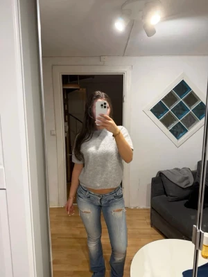 Ljusblå slitna bootcut jeans - Ny annons med fri frakt !! Säljer ett par ljusblå bootcut jeans med slitningar på knäna och lätt tvättad look. Jeansen har låg midja och klassisk femficksdesign. Perfekta för en avslappnad och trendig stil. 