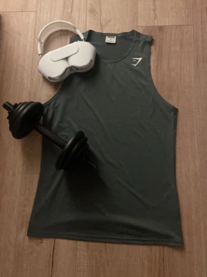 Mörkgrå Gymshark träningslinne - Säljer ett mörkgrått träningslinne från Gymshark i storlek XS. Linnet är ärmlöst och har en rund halsringning, perfekt för gymmet eller löpning. Materialet är mjukt och stretchigt för maximal rörelsefrihet. Diskret Gymshark-logga på bröstet.