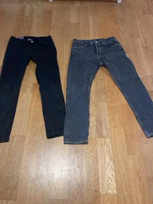 Jeans - Säljer ett par svarta slim jeans från Lee med klassisk femficksdesign och knappstängning. Jeansen har en smal passform och är tillverkade i bomull med lite stretch för extra komfort. Perfekta för dig som gillar en stilren look. Storlek 31/30 på dem gråa storlek 32/30 på dem svarta