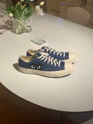 Blå Converse x CDG Play sneakers - Snygga blå Converse x Comme des Garçons Play sneakers med det ikoniska hjärtögat på sidan. Låga med vita snören och tå, samt vit sula. Klassisk canvasmodell som är både stilren och trendig. Storlek 46,5