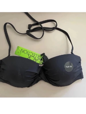 Svart bikini  push up-bh  - Snygg svart push up-bh från Black Collection med avtagbara och justerbara axelband. Bh:n har vadderade kupor och knäppe fram. Perfekt för dig som vill ha extra lyft och en clean look under kläderna.