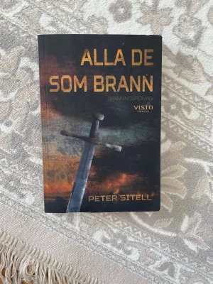 Alla de som brann av Peter Sitell - Spänningsroman med omslag i mörka färger och motiv av ett svärd mot en dramatisk bakgrund. Boken är skriven av Peter Sitell och utgiven av Visto förlag 2019. Perfekt för dig som gillar spännande och mystiska berättelser.