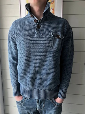 Blå stickad tröja med hög krage - Säljer en blå stickad tröja med hög krage och stora knappar från L’ Honne | skicket är utmärkt 
