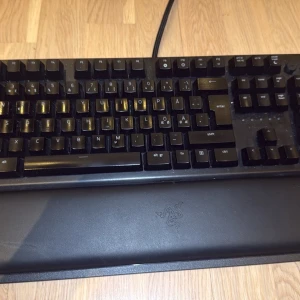 Razer tangentbord blackwidow elite  - Säljer ett svart mekaniskt tangentbord från Razer med gröna switchar och handledsstöd. Tangentbordet har nordisk layout och USB-anslutning. Perfekt för gaming eller skrivarbete med snabb respons och snygg design.