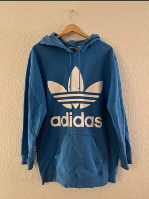 Adidas originals - En hoodie från adidas originals i strl 38. Den klassiska adidas-blåa färgen. Lite längre i modellen.   Sparsamt använd och i gott skick. Hittar ingenting att anmärka på.
