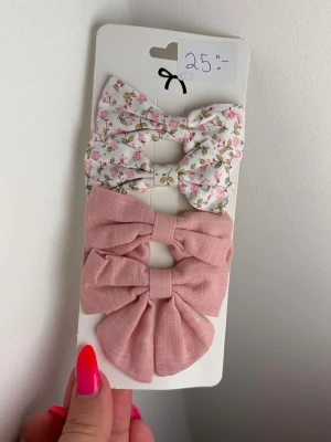 Set med 4 stora hårrosetter - 4 stora hårrosetter på klämma, en i ljusrosa tyg och en i vitt tyg med små rosa blommor och gröna blad. Perfekta för att piffa till frisyren och ge en söt touch till din look. Rosetterna är gjorda i tyg och har metallclips på baksidan för enkel användning.