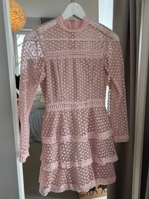 Rosa spetsklänning med volanger - Söt rosa kortklänning med långärmad spets och volangdetaljer. Klänningen har dragkedja i ryggen. Från AX Paris, storlek xs (6 uk).