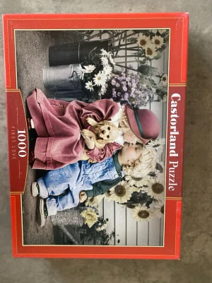 Castorland pussel 1000 bitar - Säljer ett Castorland pussel med 1000 bitar. Motiv av två barn i vintagekläder, en flicka i rosa klänning och hatt samt en pojke i blå jeans och grön tröja, omgivna av solrosor och blommor. Perfekt för dig som gillar utmanande pussel och fina motiv.